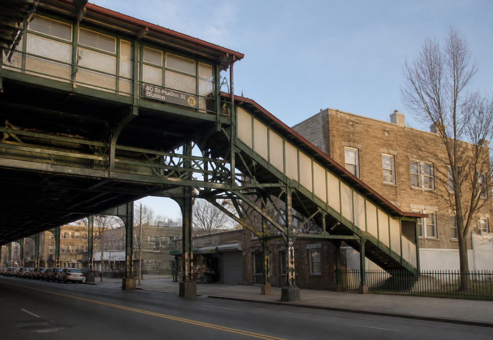An elevated station staircase and platform structure over a neighborhood avenue